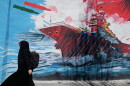 A woman walks past a mural depicting a U.S. aircraft carrier under missile attack in downtown Tehran, Iran, on June 8.