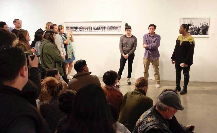 A Hill Street Country Club exhibition in February 2017 about Nguyen's time at the Standing Rock water protector protest. Pictured standing at right is Hill Street Country Club cofounder Margaret Hernandez, Nguyen, and cofounder Dinah Poellnitz.