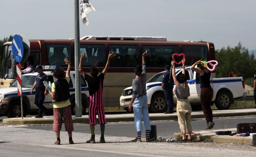 Clowns from a solidarity group wave to migrants on a bus during the evacuation of the Idomeni camp on Tuesday. Hundreds of people were put on buses heading to newly opened camps in the vicinity of Thessaloniki, Greece, about 50 miles to the south.