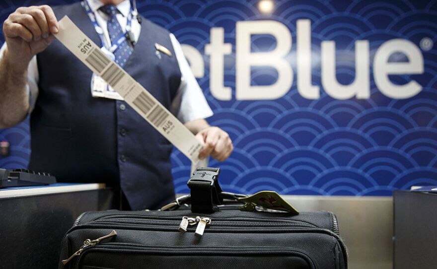 A JetBlue Airways Corp. employee tags a traveler's bag at the ticket counter inside Long Beach Airport in Long Beach, Calif.