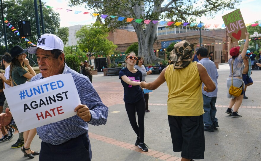 A man carrying a sign that reads "United Against Hate" dances with other demonstrators during a protest against President-elect Donald Trump in Oliveira Plaza in downtown Los Angeles on Saturday.