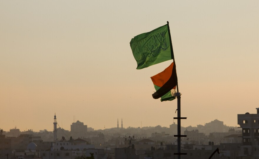 A Hamas flag, top, and a Palestinian flag fly at sundown in the Jabalia refugee camp, northern Gaza Strip, April 15, 2010.