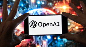 FILE - The OpenAI logo is displayed on a cell phone in front of an image generated by ChatGPT's Dall-E text-to-image model, Dec. 8, 2023, in Boston.