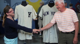 Leila Dunbar (left) appraises 1955 Whitey Ford and 1951 Yogi Berra jerseys in Omaha, Neb.