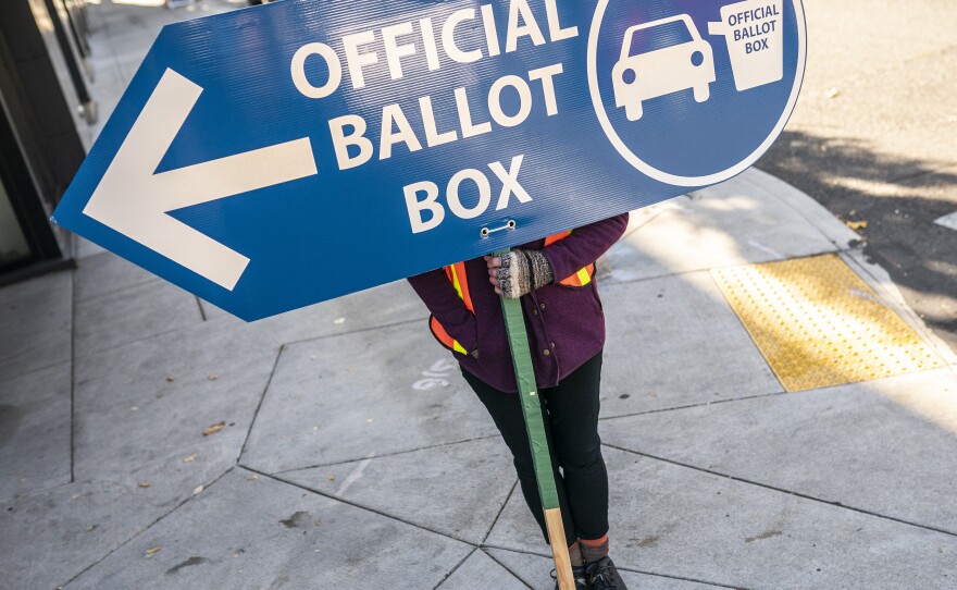An election worker directs voters to a ballot drop-off location in 2020 in Portland, Ore. Oregon is among the states waiting for the Biden administration to greenlight plans to automatically register eligible voters when they apply to enroll in Medicaid.