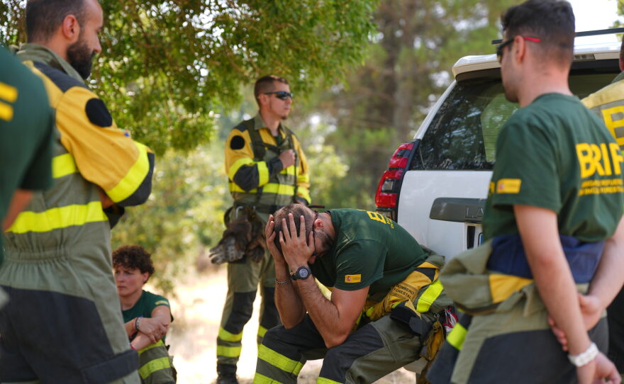 Aesir Diaz, 31, a technician with Spain's Forest Fire Reinforcement Brigades (BRIF), center, sits next to teammates during a break from battling a wildfire in Sotillo de Adrada, Ávila province, Spain, as the fire continues to spread, Tuesday, July 28, 2026.