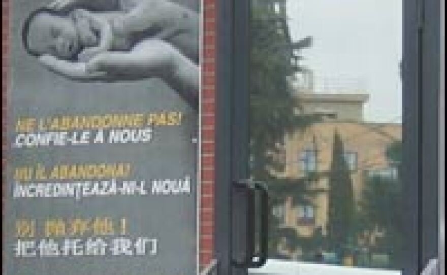 A streetside view of a 'baby box' in Rome, where mothers can safely abandon their children. Printed in six languages, the poster reads: "Don't abandon your baby. Leave it with us."