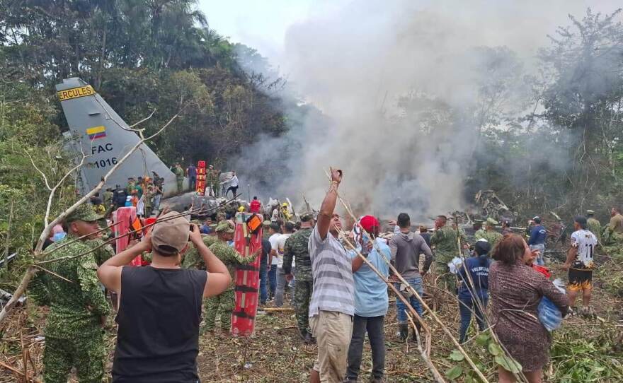 People stand around a military cargo plane that crashed after taking off from Puerto Leguizamo, Colombia, a remote municipality in the Amazonian province of Putumayo, Monday, March 23, 2026.