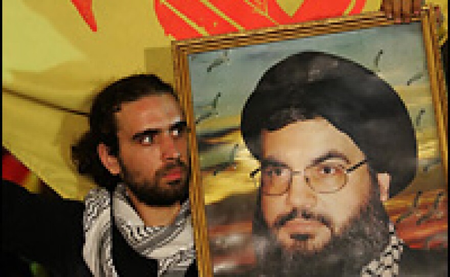 Lebanese Shiite men wave Hezbollah flags and hold up portraits of Sheikh Hassan Nasrallah during a religious festival in a southern suburb of Beirut on Monday.