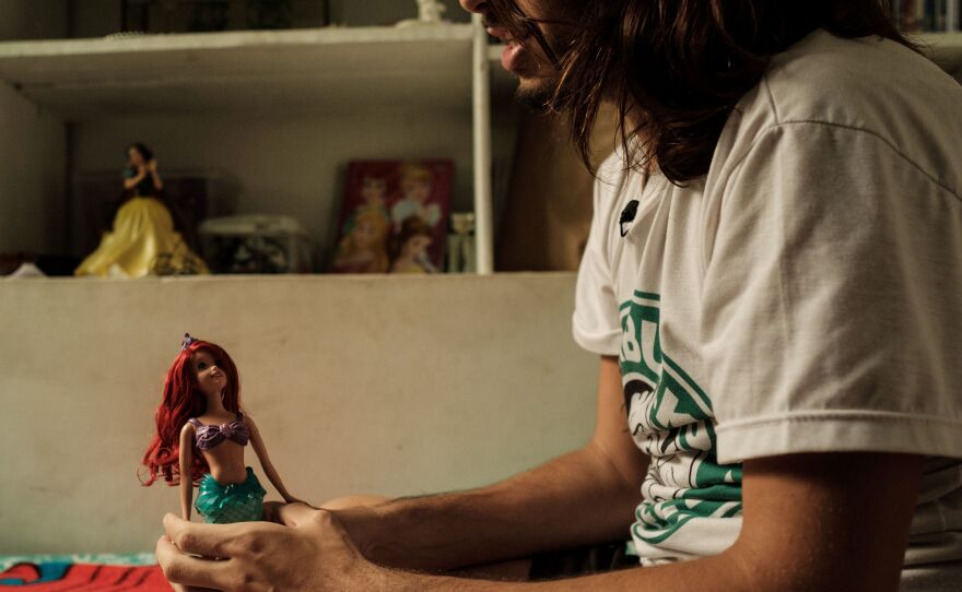 "Merman" Davi de Oliveira Moreira holds a doll of Ariel from Disney's <em>The Little Mermaid</em> at his home in Rio de Janeiro, Brazil, on May 3. The 22-year-old Brazilian is part of a growing mermaid craze in Brazil.