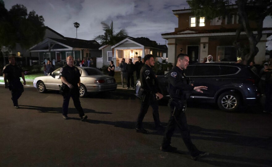 Law enforcement officials respond to an address connected to Cole Tomas Allen, the shooting suspect at the White House Correspondents' Dinner, as people stand and watch on Saturday in Torrance, Calif.
