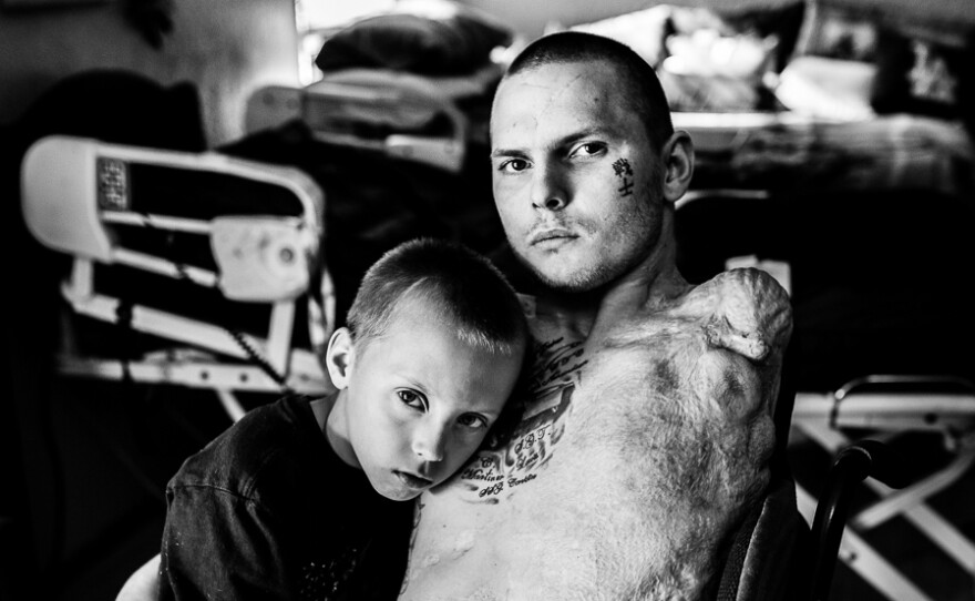 Army Spc. Jerral Hancock sits for a portrait with his son Julius. It is believed that Hancock was trapped under the wreckage of his Army tank for half an hour before he was rescued.