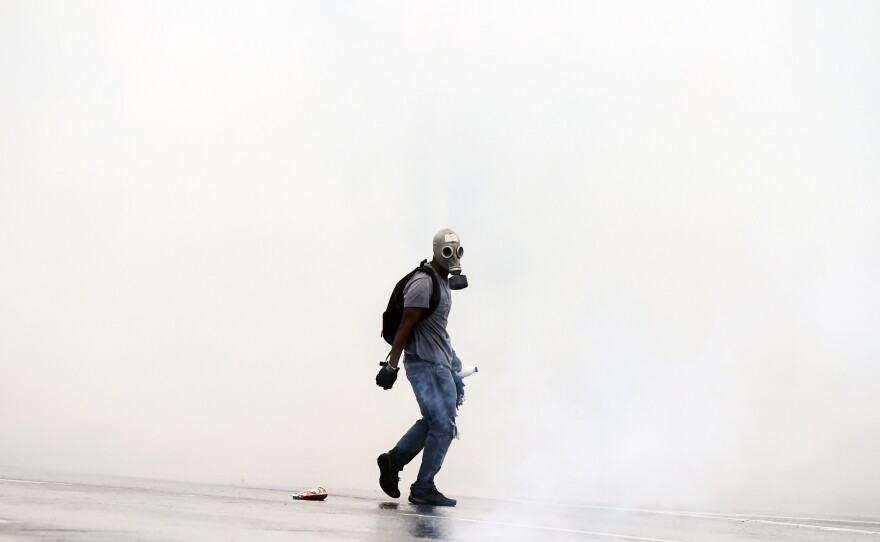 A protester stares down riot police behind his gas mask, during demonstrations against Venezuelan President Nicolas Maduro in Caracas on Thursday.