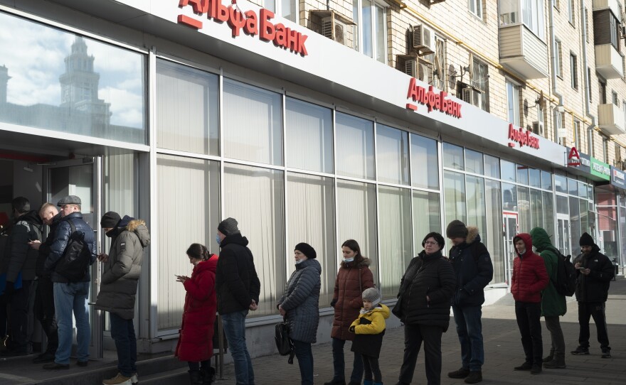 People stand in line to withdraw money from an ATM of Alfa Bank in Moscow on Sunday. Russians flocked to banks and ATMs shortly after Russia launched an attack on Ukraine and the West announced severe sanctions.