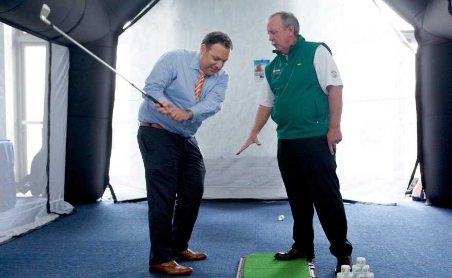 Eric Werwa, left, Deputy Chief of Staff for Rep. Mike Honda, D-Calif., gets some tips on his swing from a PGA professional at the National Golf Day event on Capitol Hill.