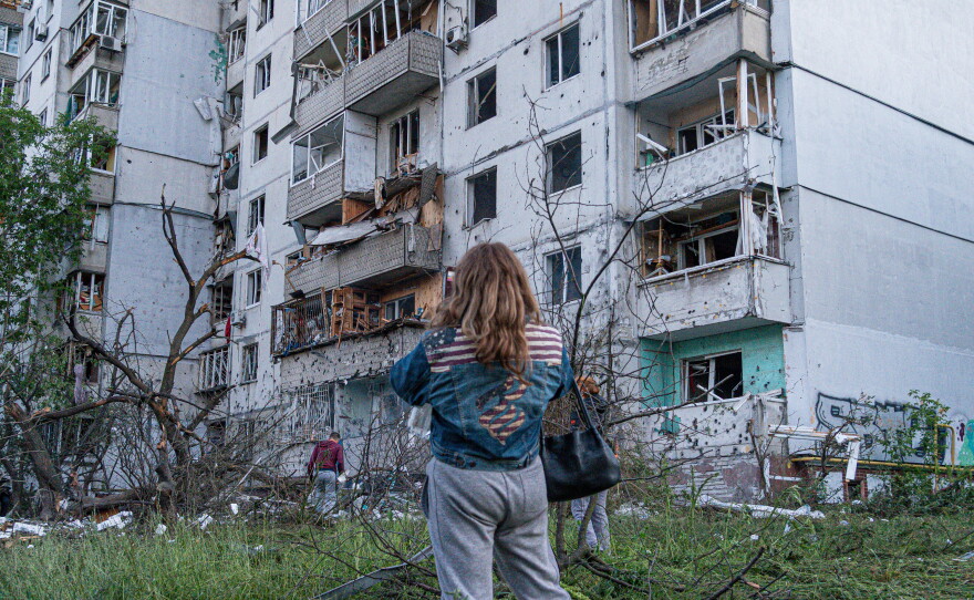 A woman stands outside of an apartment building after the night attack on Kyiv, Ukraine.