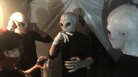 Beth Accomando in discussion with three actors dressed as Aliens in this photo from October 31, 2019