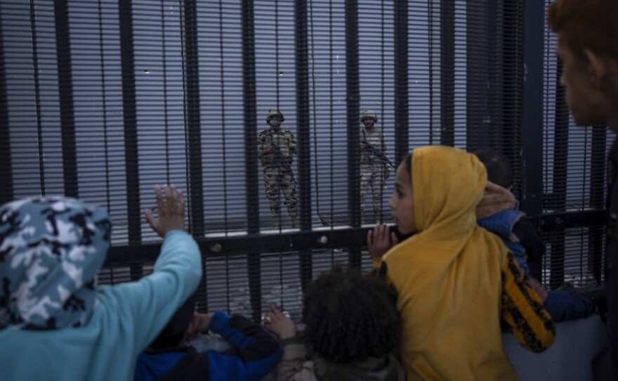 Displaced Palestinians at the southern end of Gaza look through the border fence at Egyptian soldiers on the other side on Jan. 14.