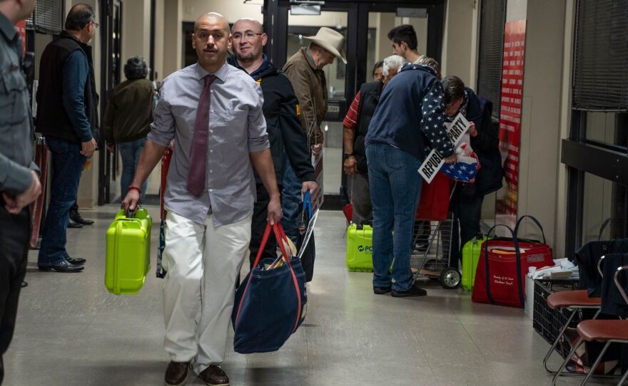 Election officials carrying equipment during last month's presidential primary in El Paso. A Texas judge says he will allow all voters to apply for absentee ballots in light of the coronavirus pandemic. The state typically makes it difficult to cast such ballots.