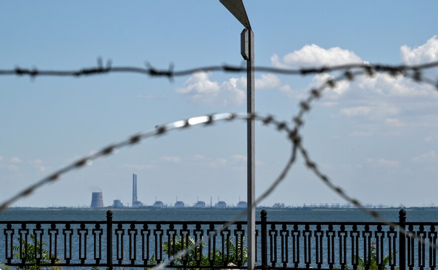 The Zaporizhzhia nuclear power plant in Ukraine's Enerhodar, Zaporizhzhia region, is seen through barbed wire on the embankment in Nikopol, Dnipropetrovsk region, central Ukraine, on July 20. Russian soldiers have been shelling Nikopol from the premises of the nuclear power plant.