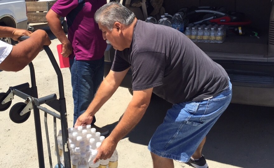 Pastor Frank Olmedo of the Spanish Church of the Nazarene in Porterville Calif., loads cases of bottled water into Humberto Hernandez's suburban. These aid stations are a lifeline here, where residents like Hernandez have been living without water for more than six months.