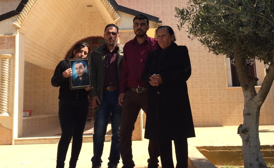 Georgette Melki and her surviving children hold a picture of her son, who was one of at least three people killed after ISIS overran a string of Assyrian Christian villages last year.