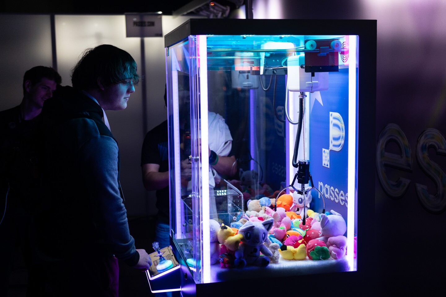 A convention attendee plays a claw maching game in the main exhibit hall of the San Diego Convention Center on Oct. 17, 2025.