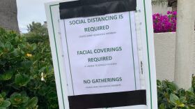 A sign reminding beachgoers to social distance and to wear facing coverings is displayed near a Del Mar Beach entrance, June 28,2020.