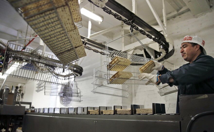 Edwin Caballeros loads fresh-baked matzos into a packaging machine at the Streit's factory in New York, March 4, 2015.