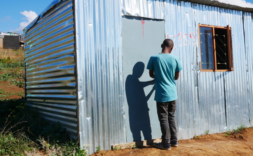 Ayanda stands in the doorway of a shack that he put up on illegally on privately owned farmland in Stellenbosch wine country. He says he grew tired of waiting for housing while living in Kayamandi township.