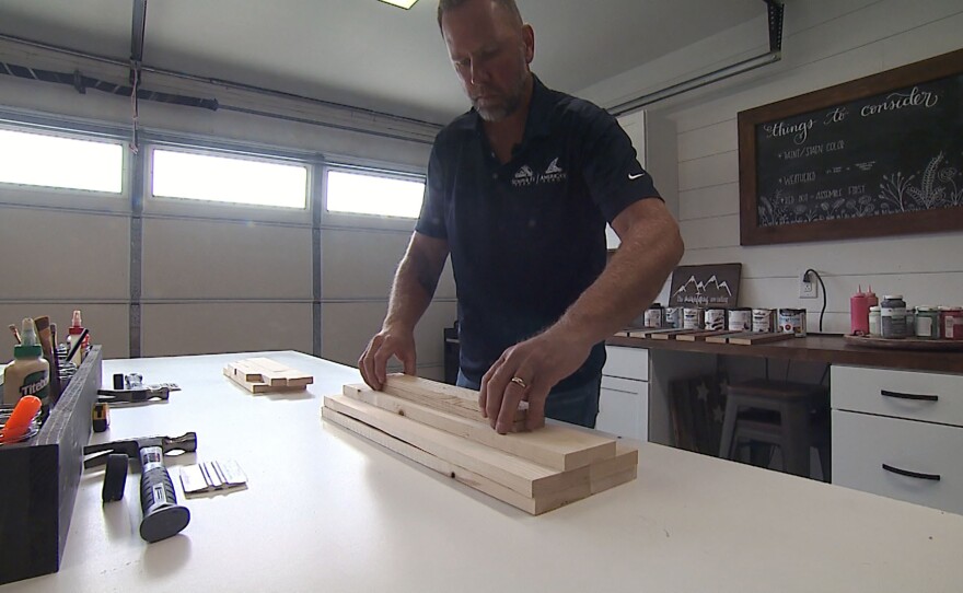 Mike Andela, former Marine, stacks a pile of wood for a workshop at his business, Coastal Sign Company, in Oceanside. April 23, 2021.