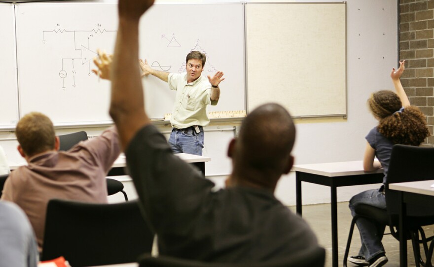 Students raise their hands in an adult education class in this undated photo.