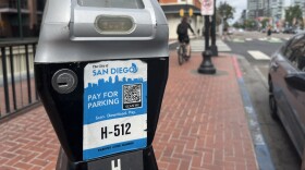 A man rides past a City of San Diego parking meter, Aug. 15, 2025.