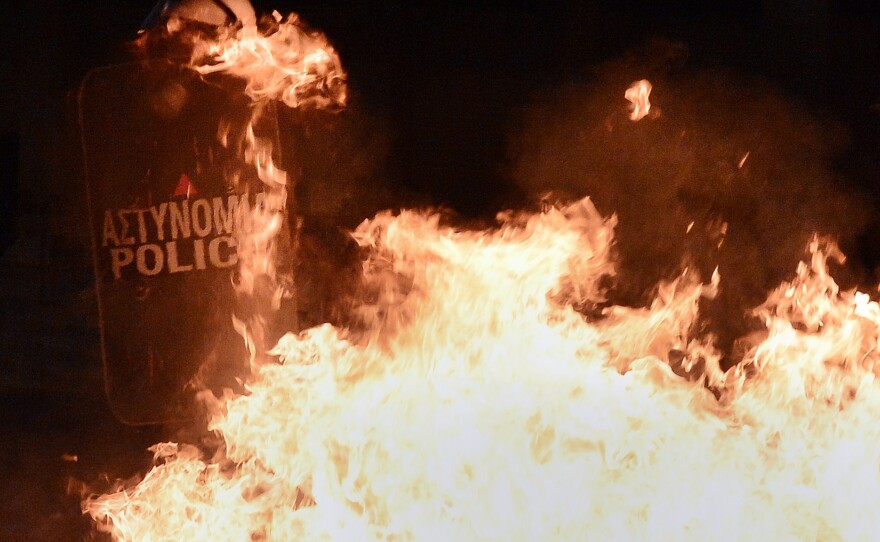 Riot police use their shields against petrol bombs lobbed by protesters during an anti-austerity protest on Thursday.