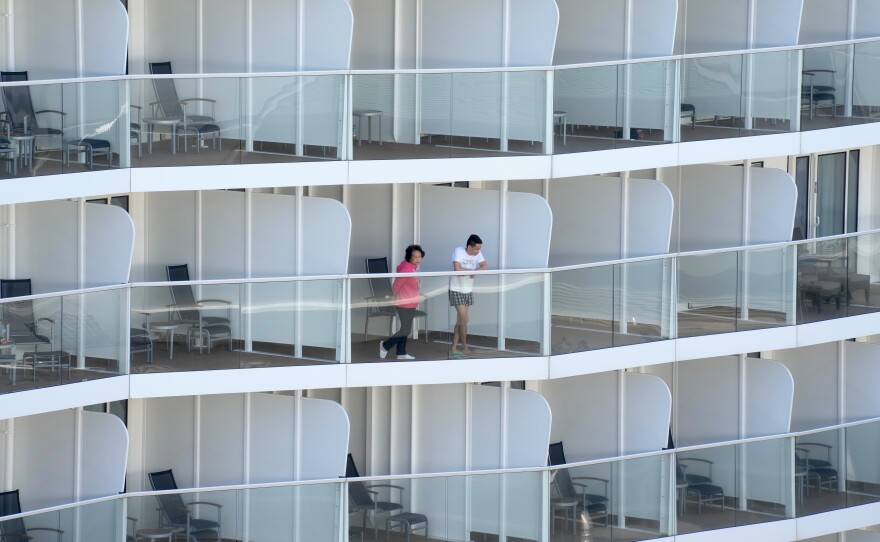 Passengers look out from the Spectrum of the Seas cruise ship docked in Hong Kong on Wednesday. Thousands of passengers were being held on the ship for coronavirus testing after health authorities said nine passengers were linked to a recent omicron cluster and ordered the ship to turn back.