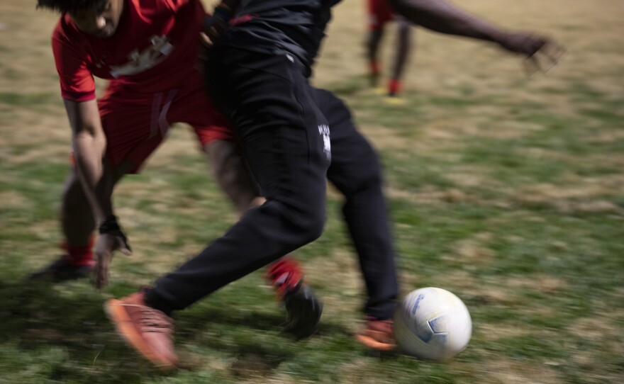Teen soccer player Raza Palmer and his coach Pierre Hedji compete for the ball.