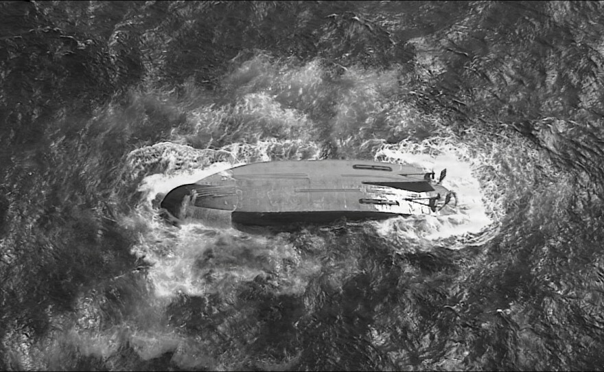 A U.S. Coast Guard HC-130 Hercules airplane crew assigned to Coast Guard Air Station Barbers Point flies over an overturned vessel offshore Saipan, Saturday, April 18, 2026, while searching for a missing vessel, the Mariana, that experienced an engine failure April 15.