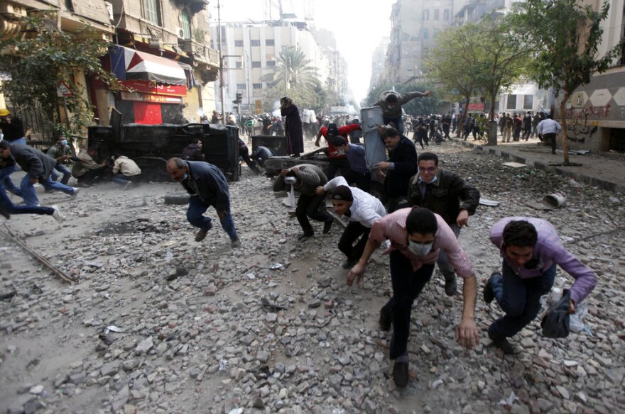 Protesters run for cover during clashes with Egyptian riot police Tuesday near Tahrir Square in Cairo.