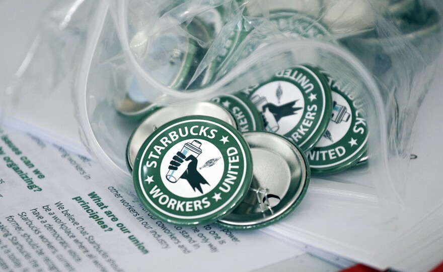 Pro-union pins sit on a table during a watch party for Starbucks' employees union election in December in Buffalo, N.Y. Starbucks union organizers say the company is closing a New York store to retaliate.