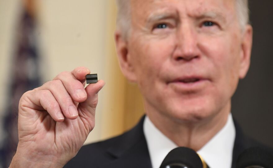 President Biden holds a semiconductor chip in this 2021 file photo. The White House is working out how to spend $52 billion that Congress has provided to spur U.S. chip manufacturing plants.