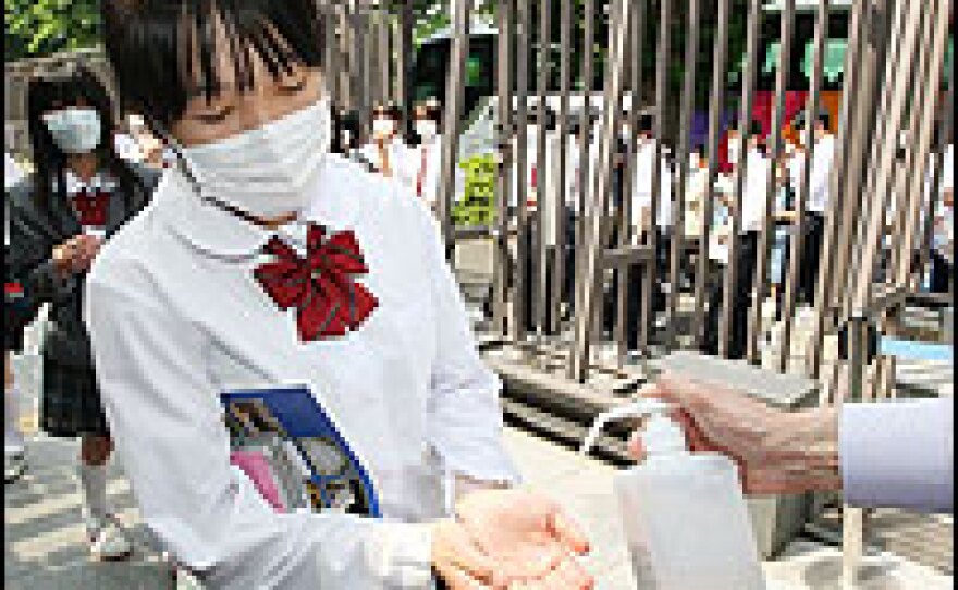 Middle school students wearing face masks get their hands disinfected by a security guard during their visit to the House of Councillors on Thursday in Tokyo. In order to prevent the spread of swine flu, the House of Councillors is giving visitors face masks.