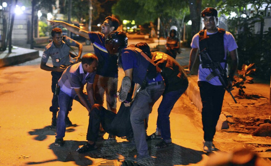People help an unidentified injured person after gunmen attacked a cafe popular with foreigners in Bangladesh's capital, Dhaka, on Friday.