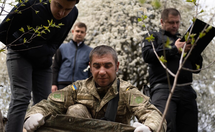 A forensic team looks under the clothing of the Russian soldier to assess the cause of death.