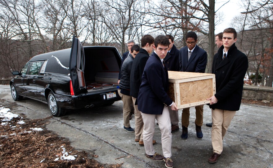 Brendan McInerney (front, from left), Noah Piou, Emmett Dalton and their fellow students from Roxbury Latin boys' school carry the casket of a man who was left unclaimed by family to a grave site in Fairview Cemetery on Friday.