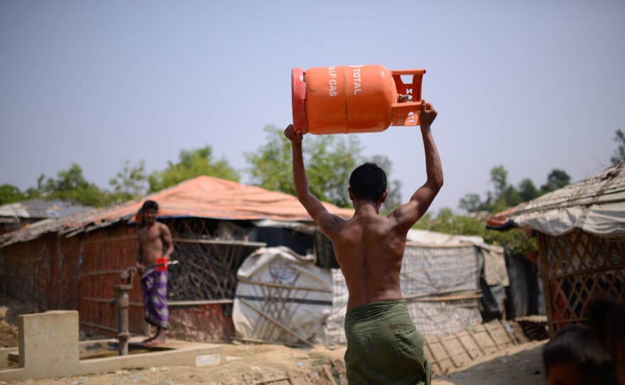 A Rohingya refugee carries a gas cylinder back to his shelter in the Balukali refugee camp. The U.N. refugee agency, along with other aid organizations, has launched a program to replace wood cooking fires with gas stoves.