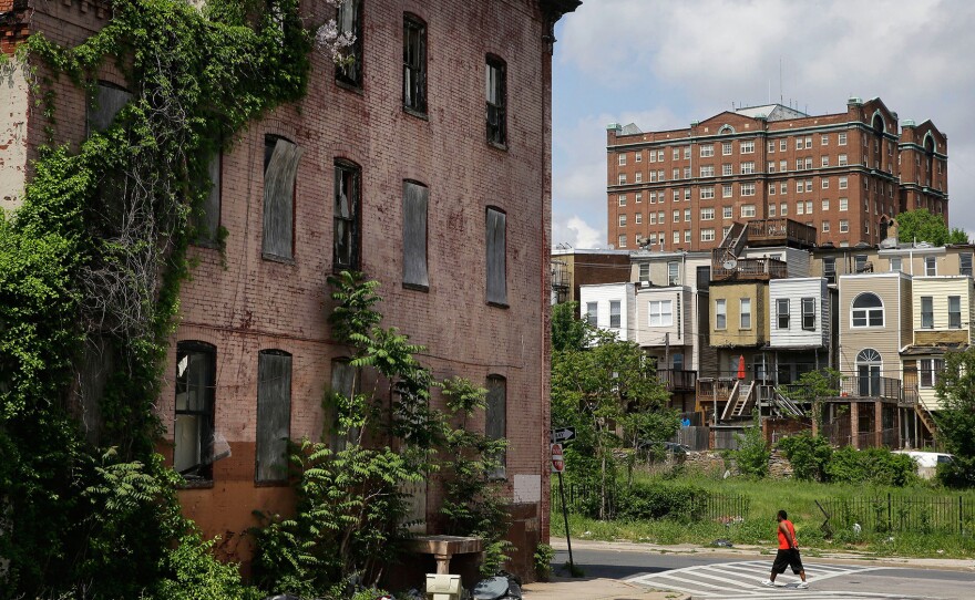 A man walks past a blighted building in the Penn-North neighborhood of Baltimore.