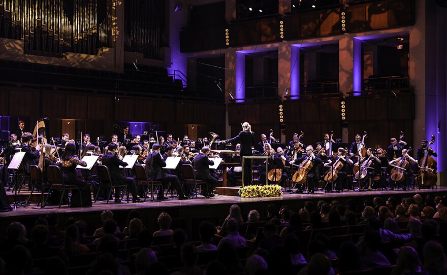 Keri-Lynn Wilson conducting with Orchestra and audience standing.