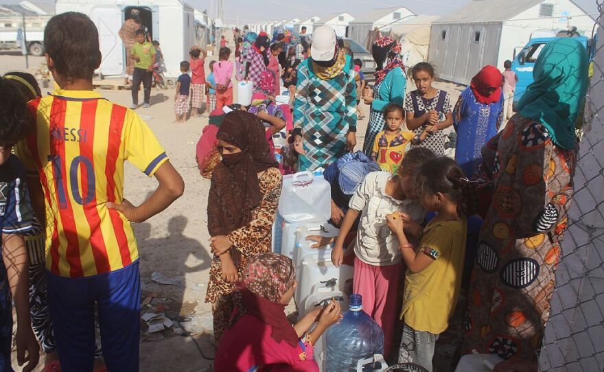 Displaced Iraqis from the Fallujah area wait to fill jerrycans with water at a camp on June 22, 2016.