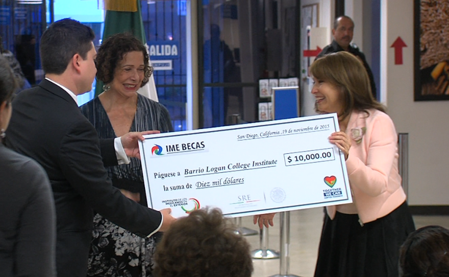 Mexican Consul General Maria de los Remedios Gómez Arnau, right, presents a check for $10,000 to the Barrio Logan College Institute, Nov. 19, 2015.