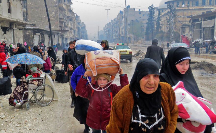 Syrian residents, fleeing violence in the Bustan al-Qasr neighborhood, arrive in Aleppo's Fardos neighborhood on Tuesday after government troops retook the area from rebel fighters.